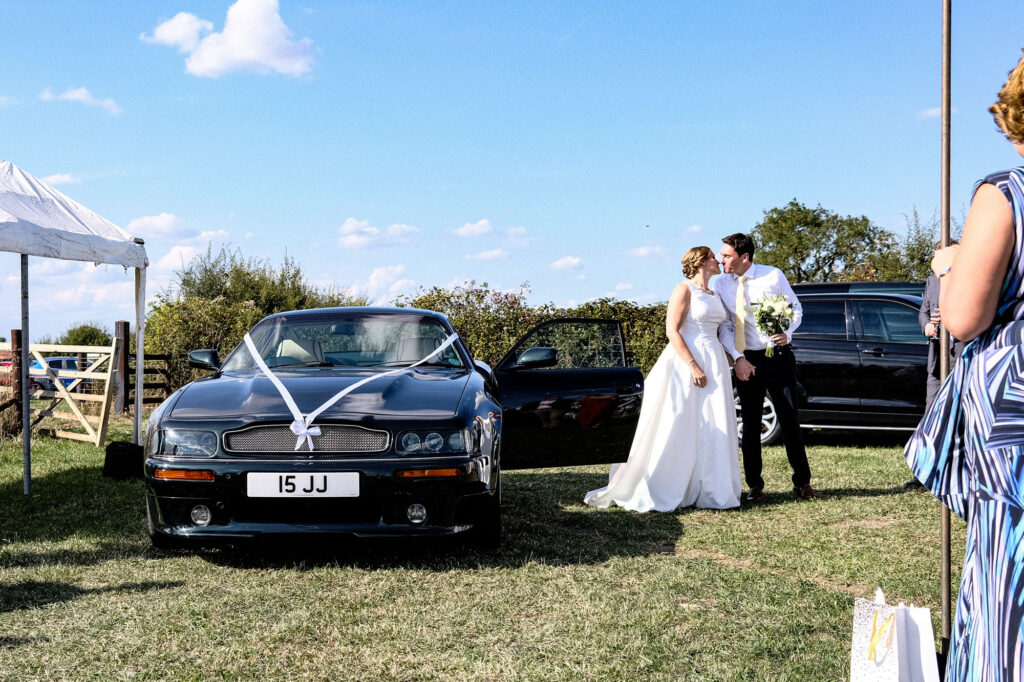 Bride and groom getting out of their Aston Martin